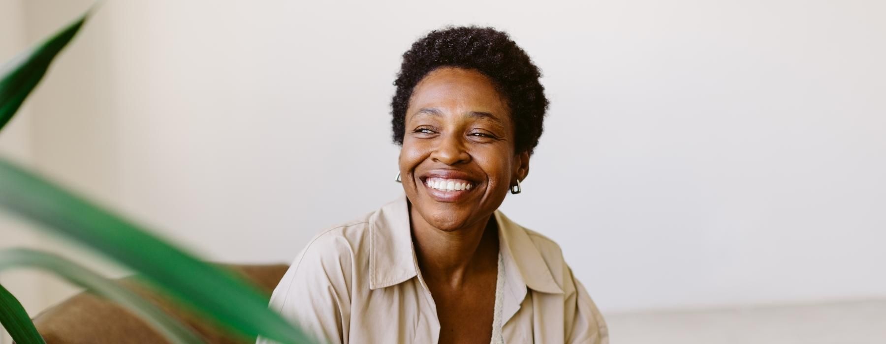 a person smiling and sitting by a plant