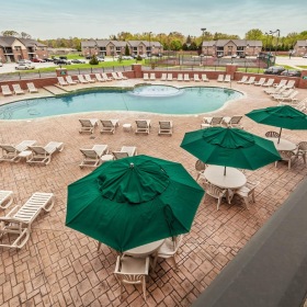 a pool with lounge chairs and umbrellas surrounding it