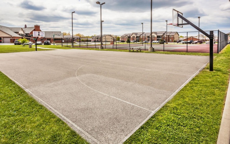 a basketball court surrounded by a green lawn