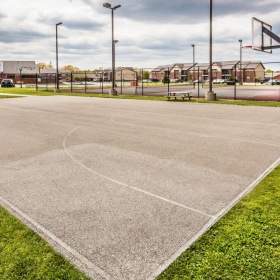 a basketball court surrounded by a green lawn